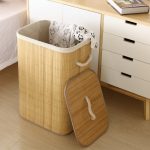 Tall natural bamboo laundry hamper with open lid in a modern bedroom setting