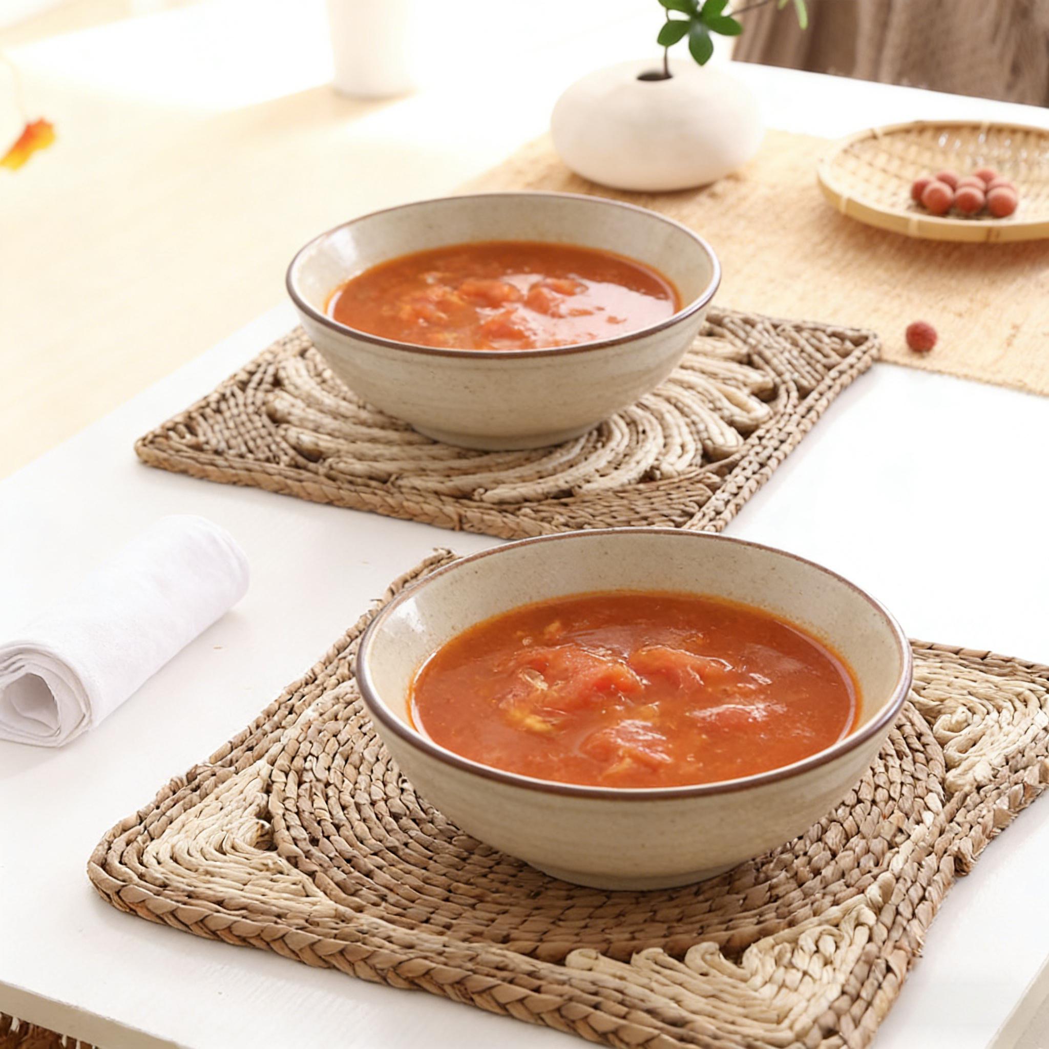Square water hyacinth placemat holding a bowl of tomato soup on a white dining table