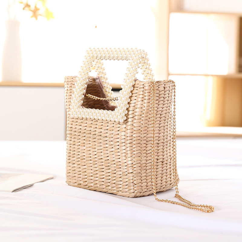 Beige pearl handle straw tote bag placed on bright bedroom bedding