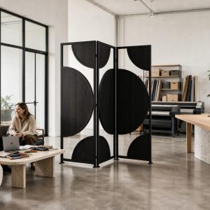Bold circle and half circle inlays on matte black room divider panels in a bright design studio