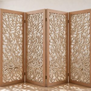 Deep relief floral cutouts in a carved wood screen in solid hardwood casting lace like shadows across a neutral living room